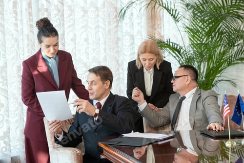 Preview: Two delegates in formalwear consulting with secretaries while reading contract