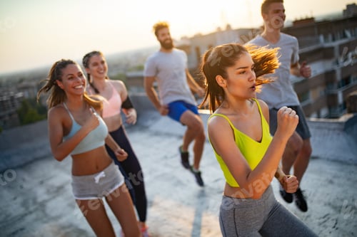 Preview: Group of young happy people friends exercising outdoors at sunset