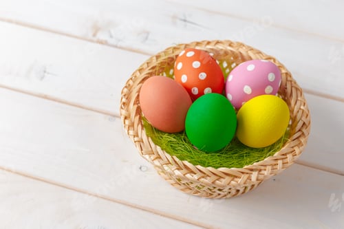 Preview: Colorful eggs in a woven basket on a wooden surface during spring celebration