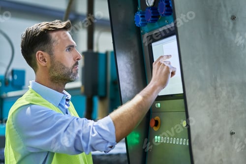 Preview: Engineer using computer and operating machinery in factory