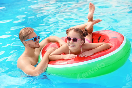 Preview: Young man with daughter in pool on sunny day