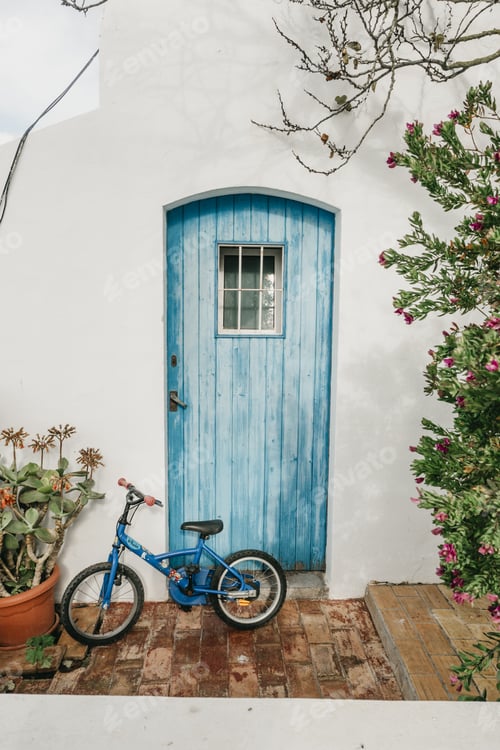 Preview: Vertical shot of an old bike leaning against a wall near a wooden door