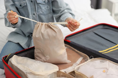 Preview: Woman with drawstring bag and suitcase indoors, closeup
