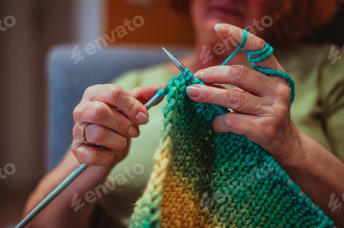 Preview: Close up of the hands of a senior woman knitting at home.