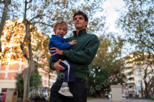 Preview: Teen Holding Smiling Child in an Urban Park