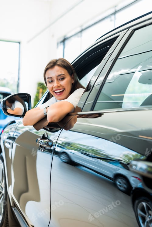 Preview: selective focus of happy woman sitting in shiny car