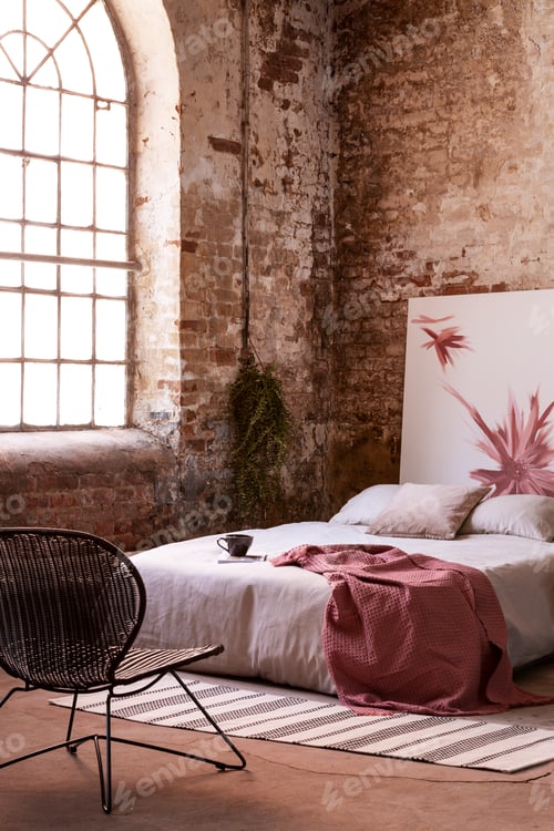 Preview: Armchair in front of bed with red blanket in industrial bedroom