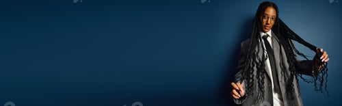 Preview: A young woman flaunts her bold fashion in a suit, playfully styling her long braids.