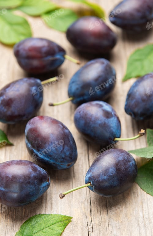 Preview: Ripe purple plums fallen on wooden table