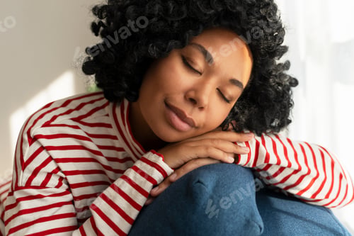 Preview: Portrait beautiful African American woman sitting on comfortable sofa eyes closed sleeping at home