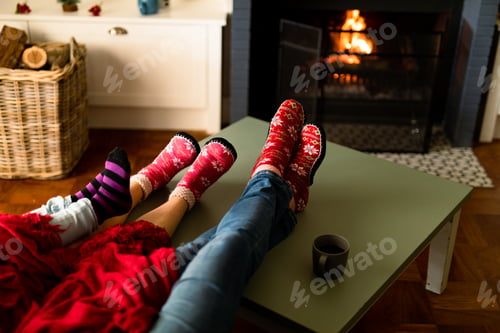 Preview: Feet of caucasian family wearing christmas socks and sitting on sofa at christmas time