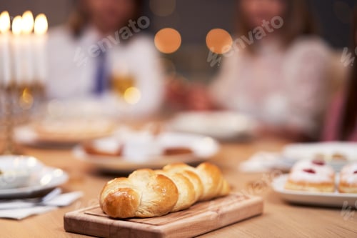 Preview: Hanukkah dinner. Family gathered around the table with traditional dishes