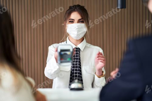 Preview: Receptionist wearing a mask working in a hotel