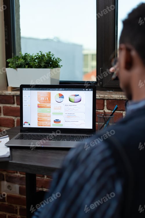 Preview: Over shoulder view of startup employee analyzing business key performance indicators on laptop