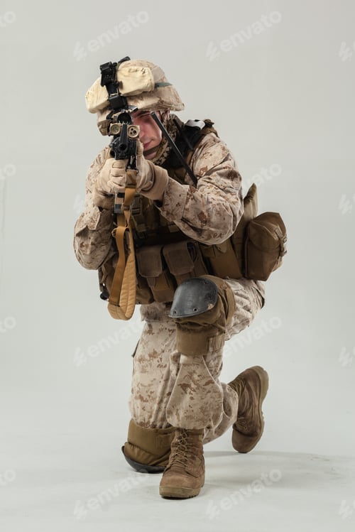Preview: Soldier in camouflage kneels and aims weapon during training at indoor location