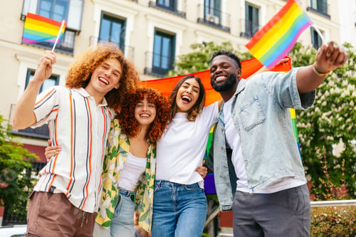 Preview: Happy multi ethnic friends celebrating lgbt pride month waving rainbow flags