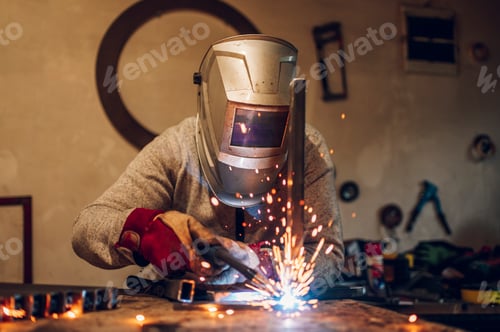 Preview: Man worker welding metal with welding machine in a factory or workshop