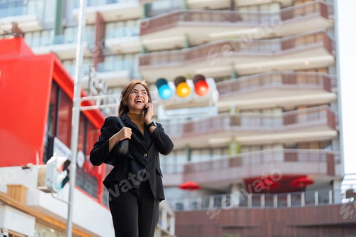 Preview: Asian professional businesswoman holding cellphone using smartphone standing or walking on big city