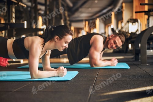 Preview: Smiling loving couple training core in gym