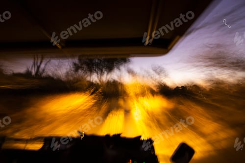 Preview: Vehicle with lights moving along a road after sunset.