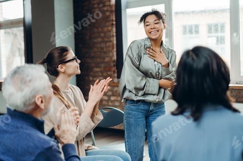 Preview: Smiling African American woman receiving applause from support group members clapping