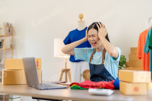 Preview: Small online business owner Asian woman stressed headache with parcel box at home.