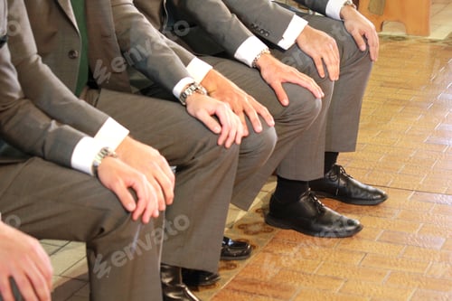 Preview: Groomsmen with hands on knees waiting for the bride to walk down the aisle at a wedding