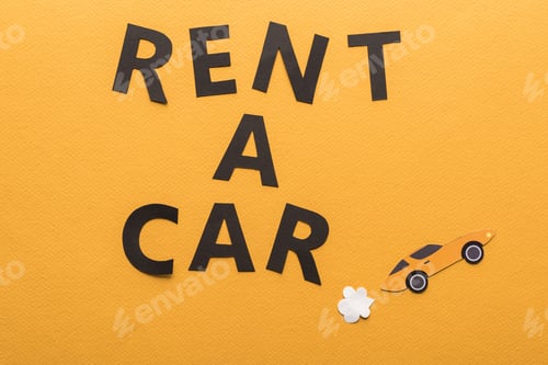Preview: top view of paper cut sports car with exhaust gas and black rent a car lettering on orange