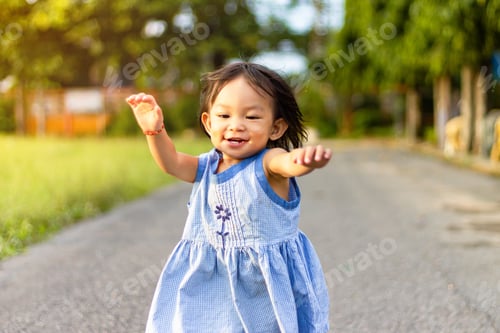 Preview: Happy Asian child girl smiling and running on the road at the park.
