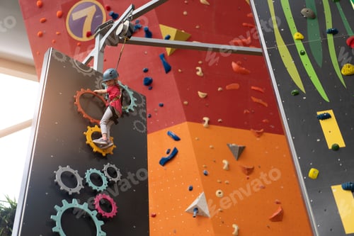 Preview: Child climbing on wall in amusement centre. Climbing training for children. Little girl in dressed