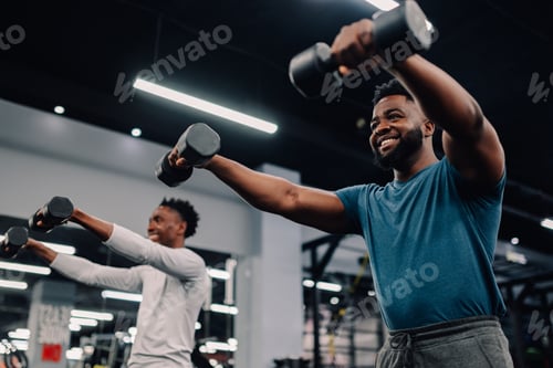 Preview: Two young men lifting weights, training together in gym