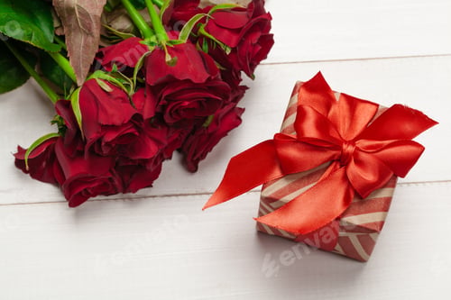 Preview: A bouquet of red roses, gift and hearts on table. Concept Women's Day or St. Valentine. Copy
