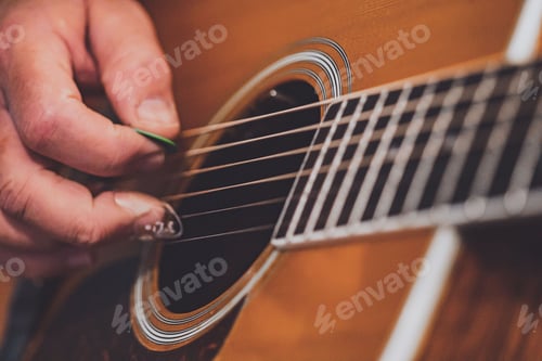 Preview: Closeup of a hand of older man picking or playing strings of acoustic guitar
