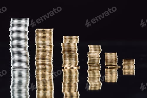 Preview: stacks of silver and golden coins on surface with reflection isolated on black