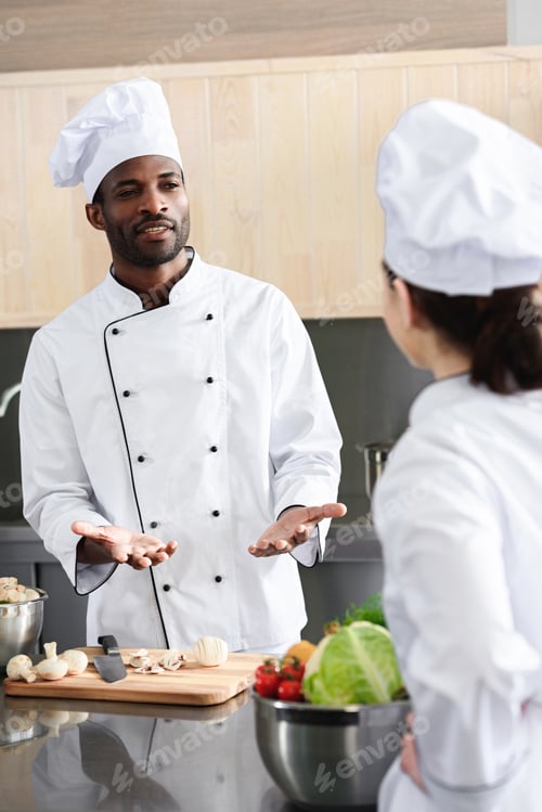 Preview: Multiracial chefs team discussing recipe and cooking on kitchen