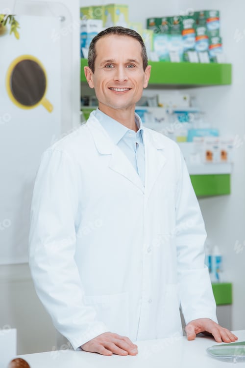Preview: portrait of smiling optometrist in white coat standing at counter in optics