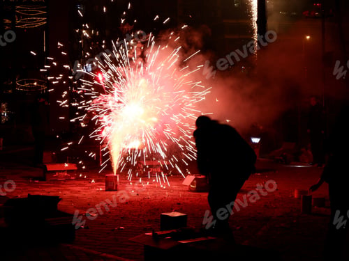 Preview: a person standing under a fire with fireworks in the air