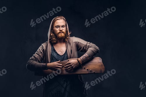 Preview: Redhead hipster male playing on a Russian traditional musical instrument - gusli