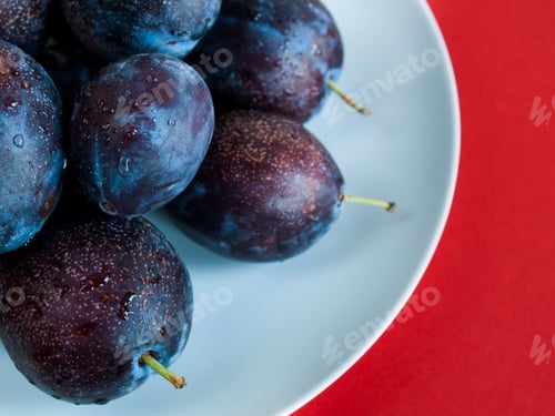 Fresh Plums with Water Droplets on White Plate
