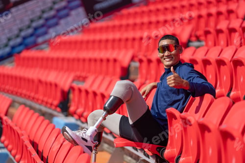Preview: Asian para-athletes with prosthetic blades sprint on standing at stadium. seats in football stadium