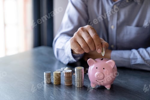 Preview: Close-up image of man hand putting coins in piggy bank for account save money. Planning step up, sav