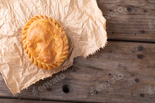 Preview: Directly above shot of baked stuffed pie on brown wax paper over wooden table