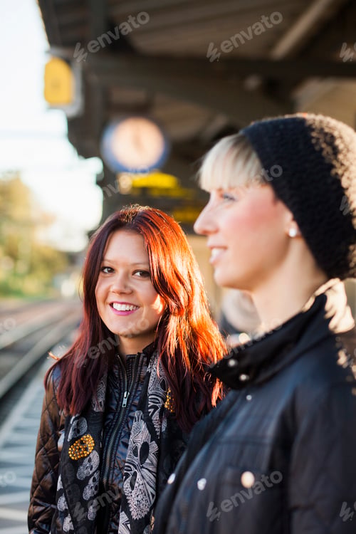 Preview: Portrait of beautiful woman with happy friend at railroad station
