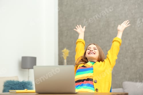 Preview: Happy young woman playing online lottery using laptop at home