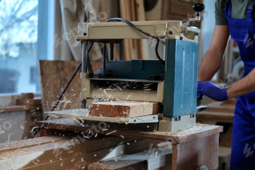 Preview: Professional carpenter working with grinding machine in shop, closeup