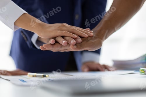 Preview: Business team joining hands over desk showing unity and teamwork.