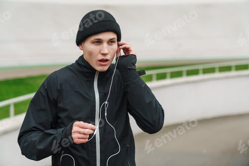 Preview: Handsome sportsman listening music with earphones while working out