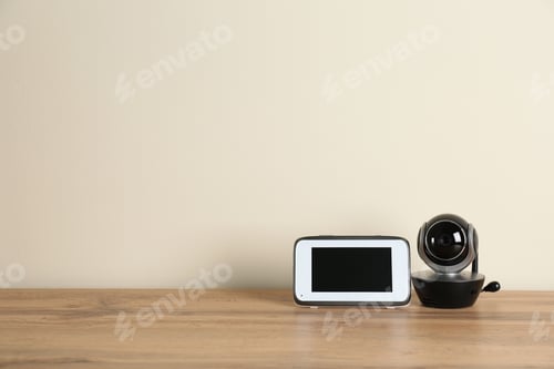 Preview: Baby monitors on wooden table, space for text. CCTV equipment