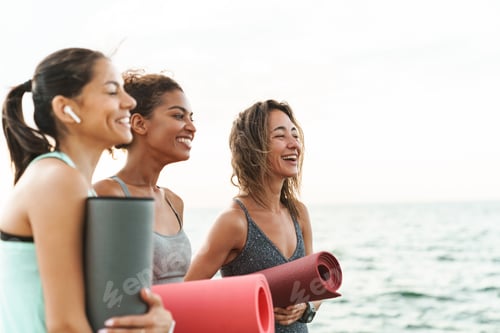 Preview: Three cheerful young sport girls standing at the beach