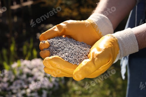Preview: Man with fertilizer in hands outdoors, closeup